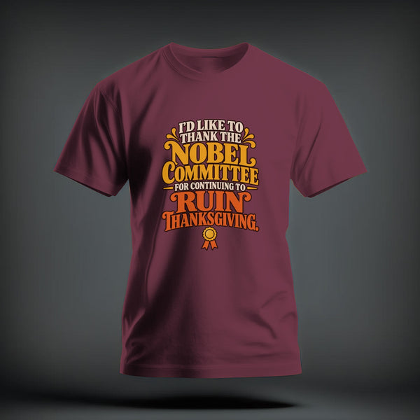 A maroon t-shirt with yellow and orange text that reads I'd like to thank the Nobel Committee for continuing to ruin Thanksgiving.